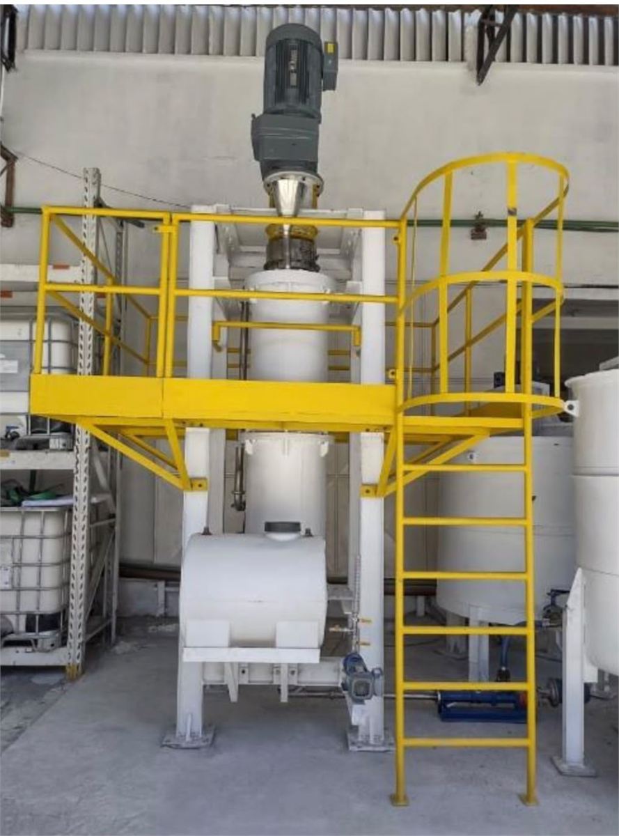 Moinho vertical branco com plataforma amarela e tanques ao lado